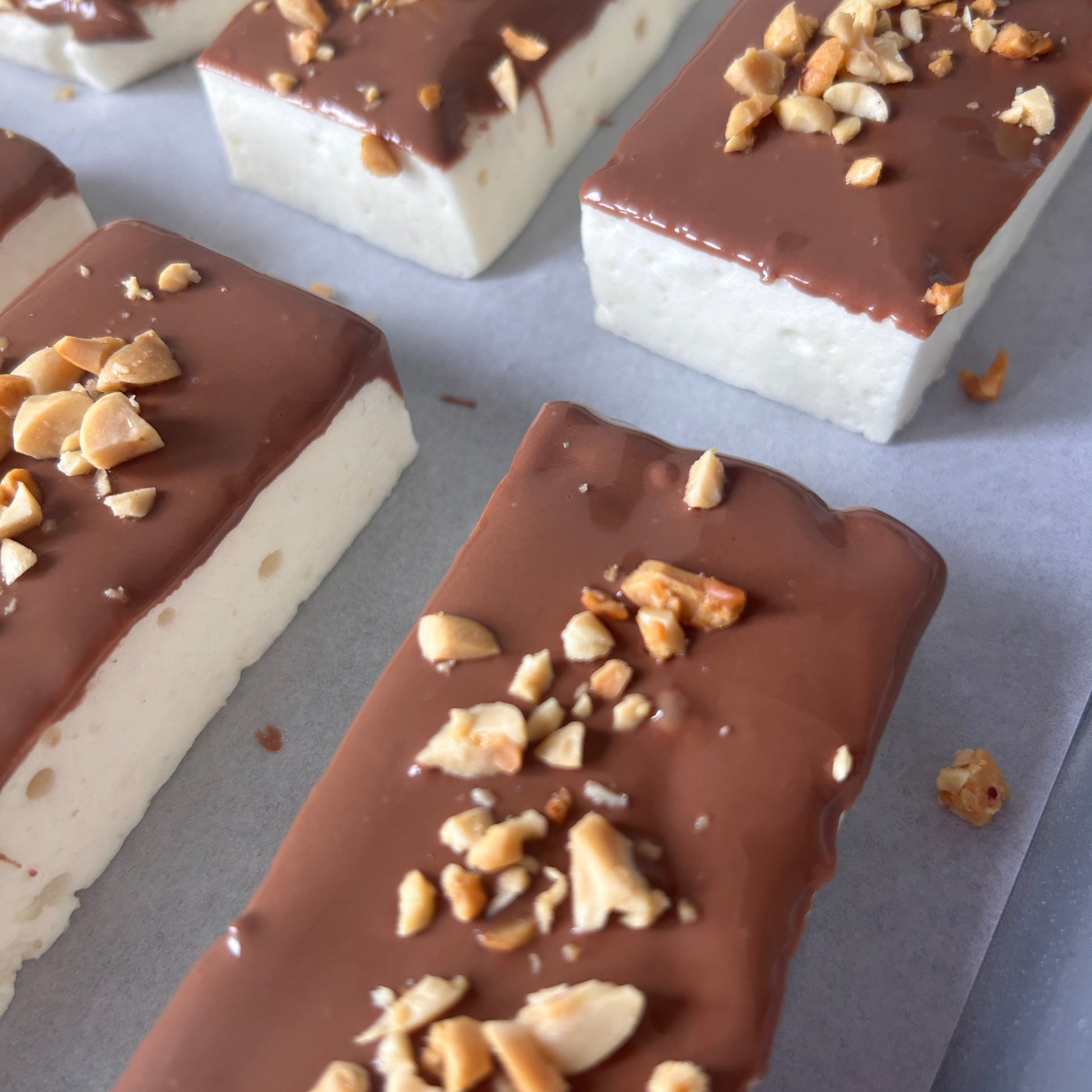 Snickers-inspired protein marshmallow with caramel flavour, milk chocolate and roasted peanuts, handmade in the UK with 9g protein and approximately 160 calories.