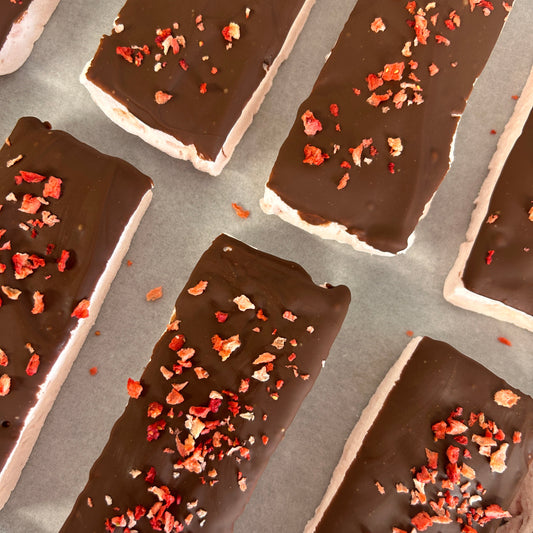 Soft strawberry protein marshmallow coated in creamy milk chocolate and topped with freeze-dried strawberries, handmade in the UK with 9g protein and approximately 160 calories.